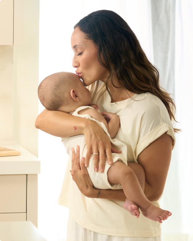 Mother kissing her newborn in a bright kitchen